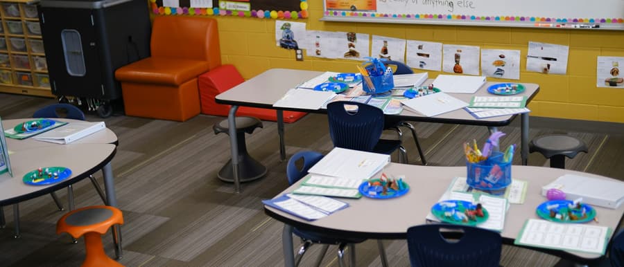 A bright primary school classroom with tables set out for a lesson