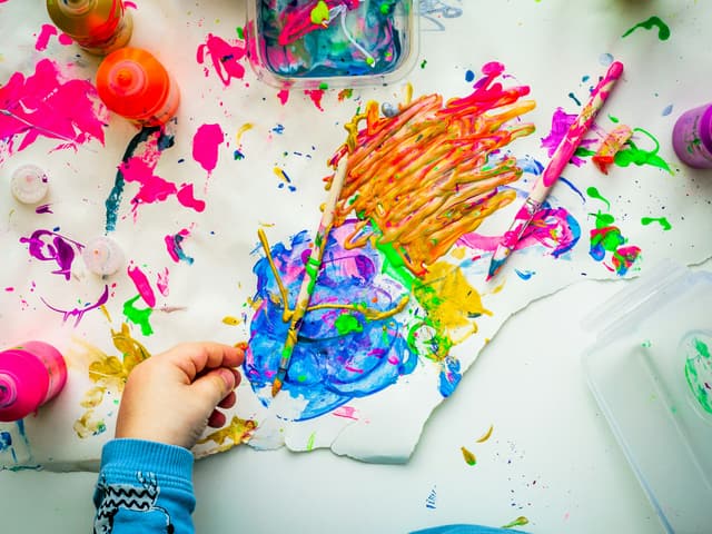 A child's hand painting with bright colours